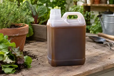 Bidon brun d’engrais liquide avec bouchon doseur posé sur un établi en bois dans un atelier de jardin